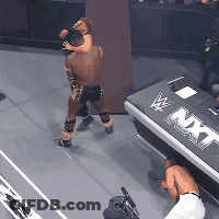 Man And Woman Wrestling In Front Of NXT Sign GIF