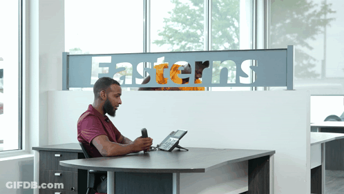 Man At Desk In Front Of Easterns Sign GIF