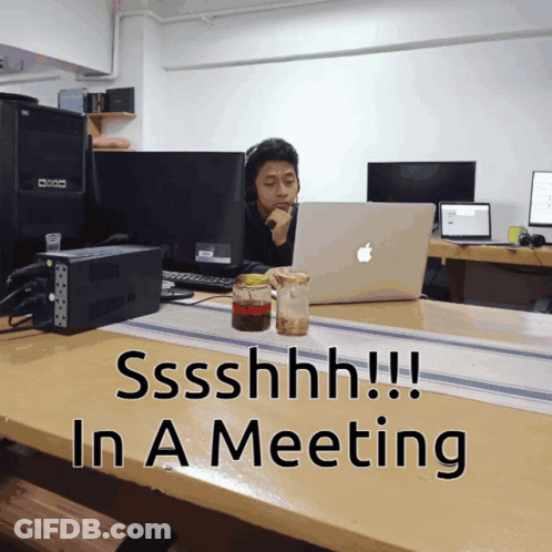 Man At Desk With Apple Laptop Saying Shhh In Meeting GIF