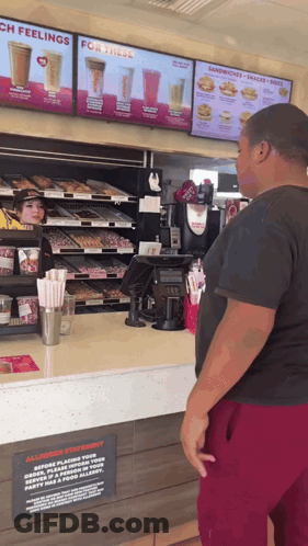 Man At Dunkin Donuts Counter Looking At Menu GIF