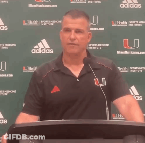 Man At Podium With Miami Hurricanes Banner GIF
