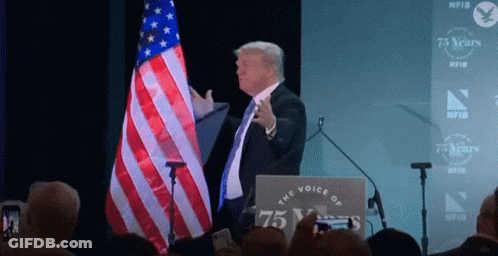 Man At Podium With Sign Saying The Voice Of 75 Years GIF
