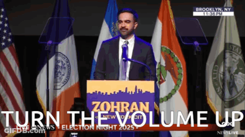 Man At Podium With Turn The Volume Up Behind Him GIF