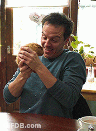 Man At Table With Coffee And 'Ee' Sign GIF