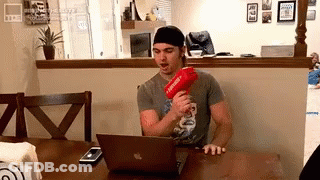 Man At Table With Laptop And Red Gun Supreme GIF