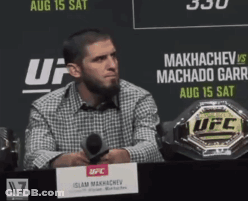 Man At Table With Microphone In Front Of UFC Sign GIF
