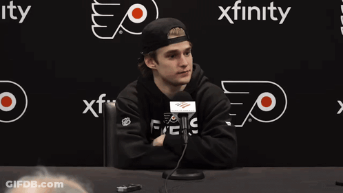 Man At Table With Microphone In Front Of Xfinity Sign GIF