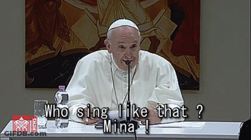 Man At Table With Microphone Saying Who Sing I Like That Mina GIF