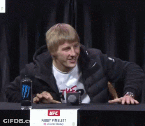 Man At Table With Paddy Pimblett Sign GIF