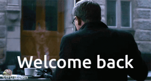 Man At Table With Welcome Back Sign GIF