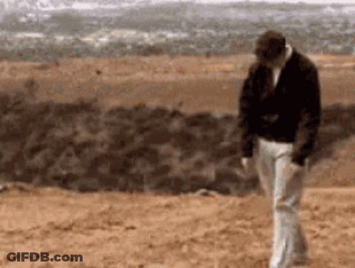 Man Black Jacket White Pants Walking Dirt Field GIF