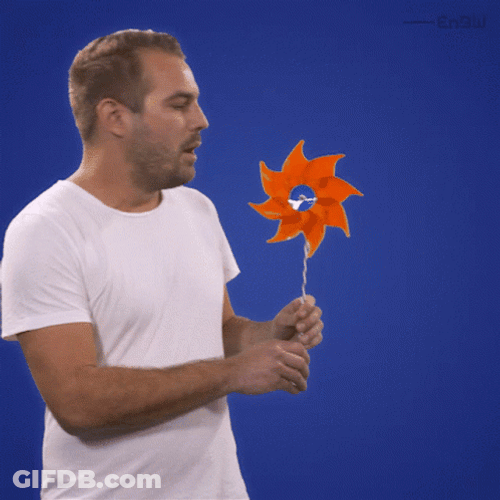 Man Blowing Hand Held Windmill GIF