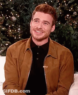 Man Brown Jacket Black Shirt Smiling On Couch GIF