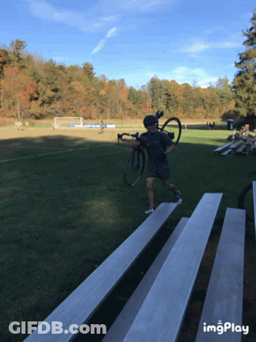 Man Carrying Bike Across Bleacher Field Imgplay GIF
