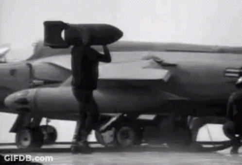Man Carrying Large Bomb In Front Of Jet GIF