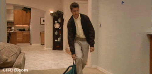 Man Carrying Suitcase Through Living Room GIF