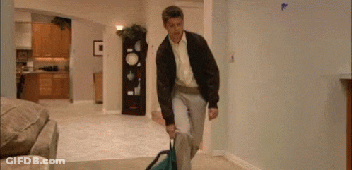 Man Carrying Suitcase Through Living Room GIF