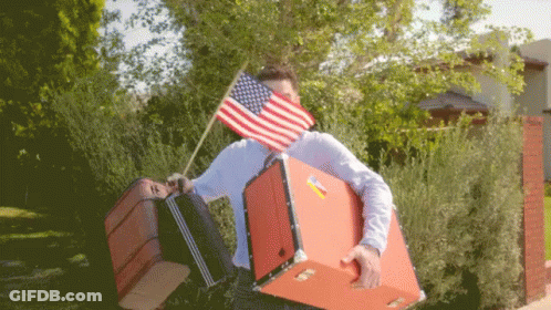 Man Carrying Suitcases With American Flag Over Face GIF
