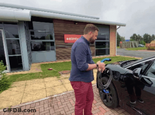 Man Charging Car In Front Of Elmt Building GIF