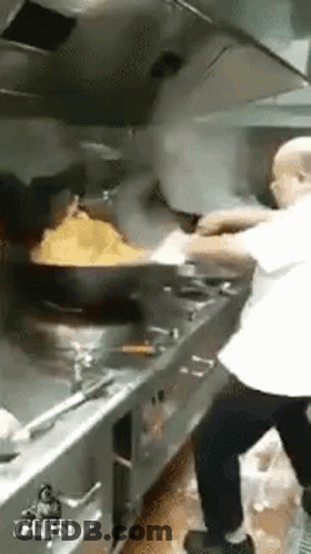 Man Cooking Food In Kitchen With Large Wok GIF