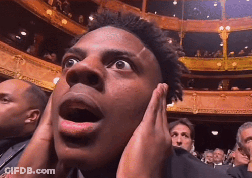 Man Covering Ears In Crowded Theater GIF