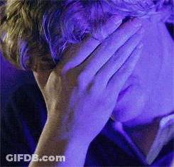 Man Covering Face With Hand In Front Of Blue Light GIF