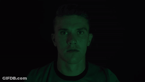 Man Covering Mouth In Dark Room With Green Light GIF