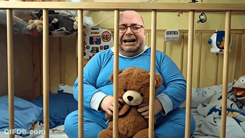 Man Crying While Holding Teddy Bear Behind Bars GIF