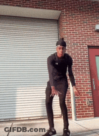 Man Dancing In Front Of Brick Building With White Garage Door GIF