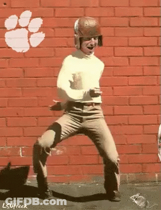 Man Dancing In Front Of Clemson Logo Brick Wall GIF