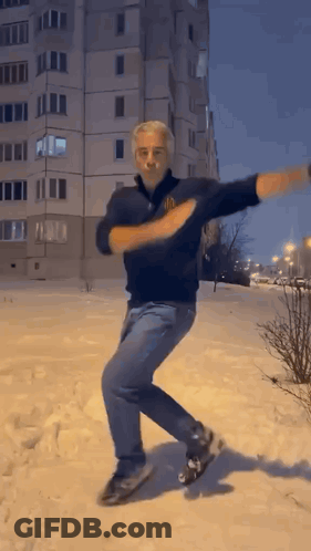 Man Dancing In Snow By Tall Building GIF