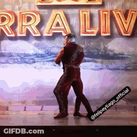 Man Dancing On Stage In Front Of Rraliv Sign GIF