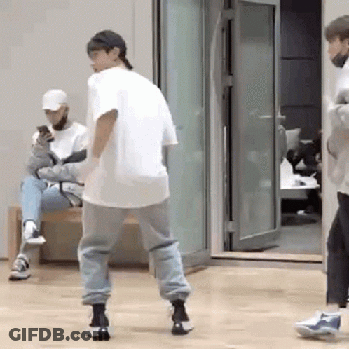 Man Dancing While Another Man Sits On Bench Looking At Phone GIF