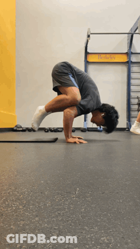 Man Doing Handstand In Front Of T-Rex Sign GIF