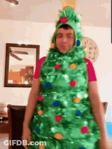 Man Dressed As Christmas Tree In Living Room GIF
