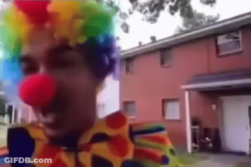 Man Dressed As Clown In Front Of Red House GIF
