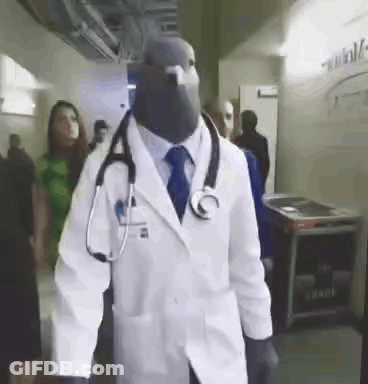 Man Dressed As Doctor With Stethoscope Walking Through Hallway GIF