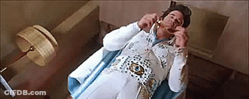 Man Dressed As Elvis Presley Laying On Bed Talking On Phone GIF