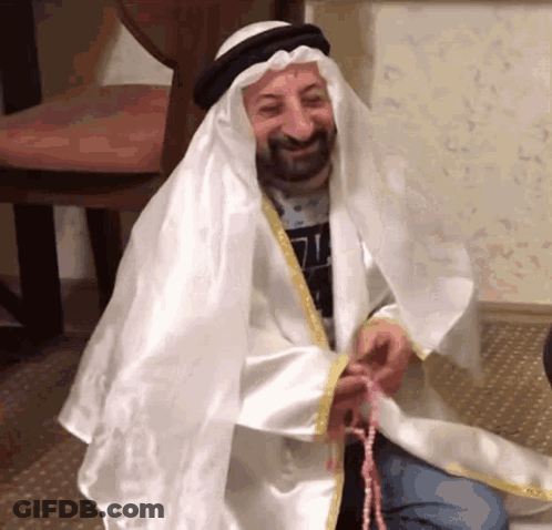 Man Dressed As Sheikh Holding Rosary And Smiling GIF