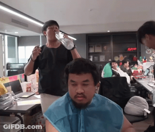 Man Drinking From Bottle While Another Shaves His Head GIF