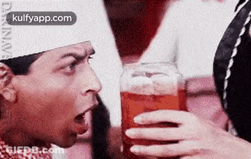 Man Drinking From Glass While Woman Holds Jar GIF