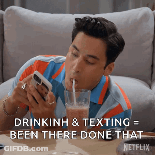Man Drinking Through Straw Looking At Phone GIF