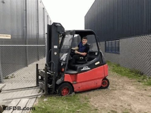 Man Driving Red Forklift In Grassy Area GIF