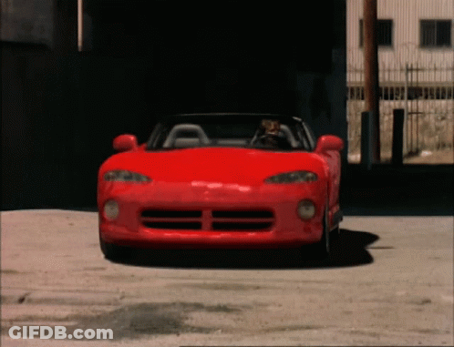 Man Driving Red Sports Car In Front Of Building GIF