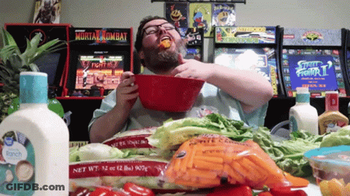 Man Eating Food In Front Of Mortal Kombat Arcade Game GIF