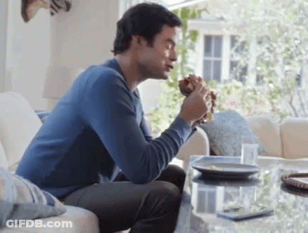 Man Eating Hamburger On Couch GIF