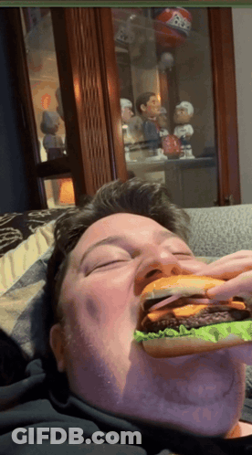 Man Eating Hamburger With Bobble Head Saying BB GIF