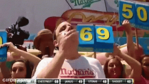Man Eating Hot Dog Holding 69 Sign GIF