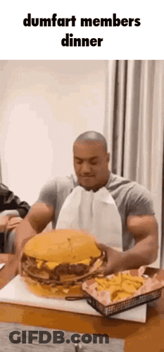 Man Eating Large Hamburger At Table GIF