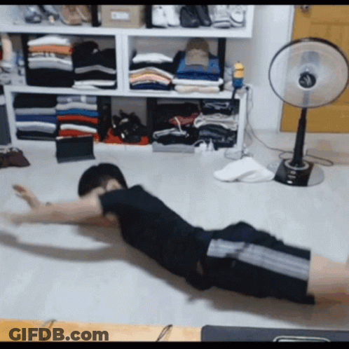 Man Exercising On Floor In Front Of Fan And Clothes GIF